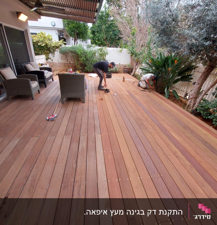 שני אנשים עובדים על דק עץ בגינה